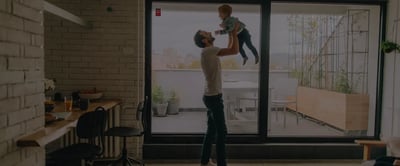 Padre che gioca col figlio in appartamento, mentre il sistema di allarme Sector Alarm garantisce sicurezza 24/7